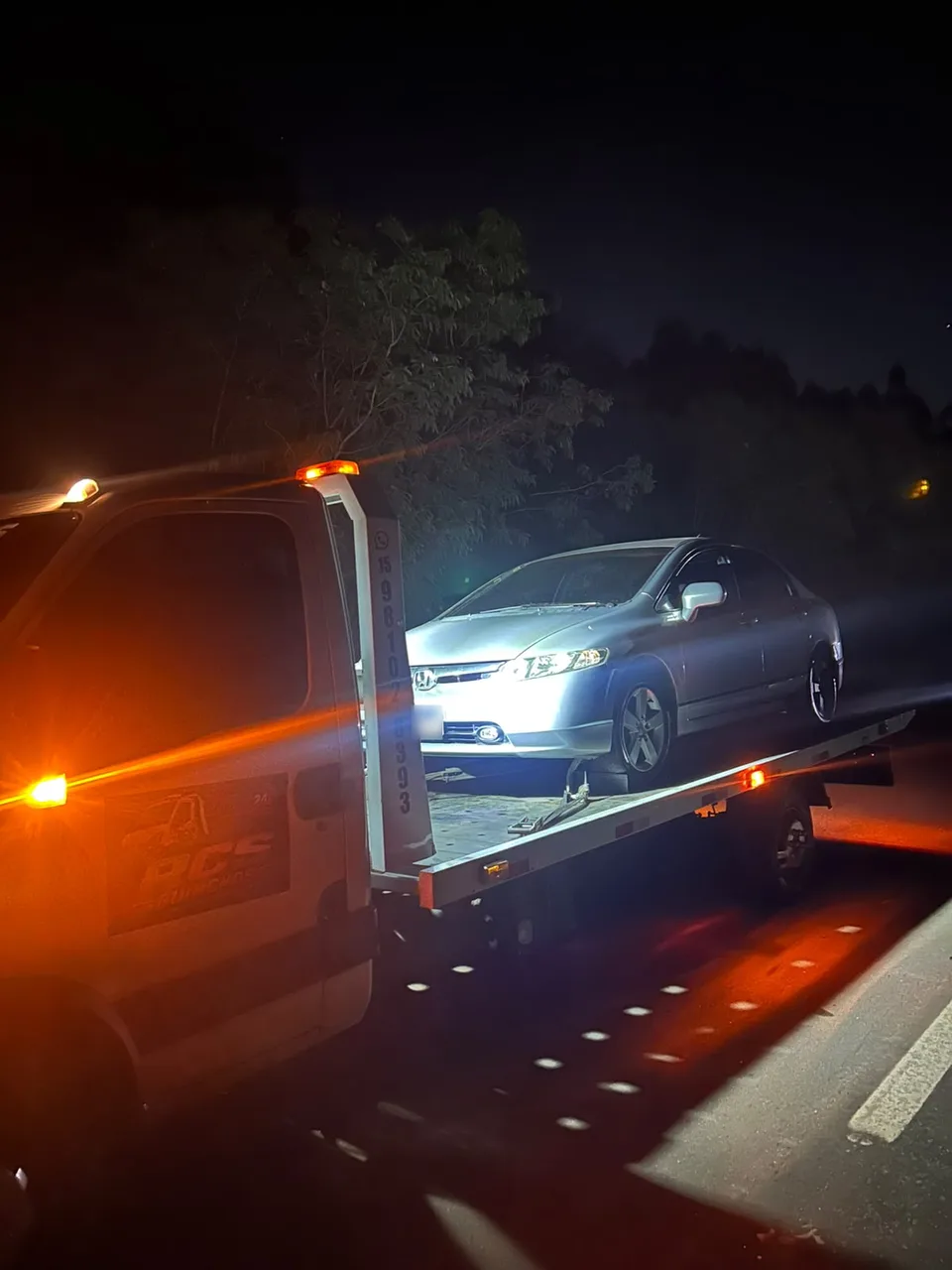Carro sobre a plataforma do guincho da RCS durante atendimento noturno