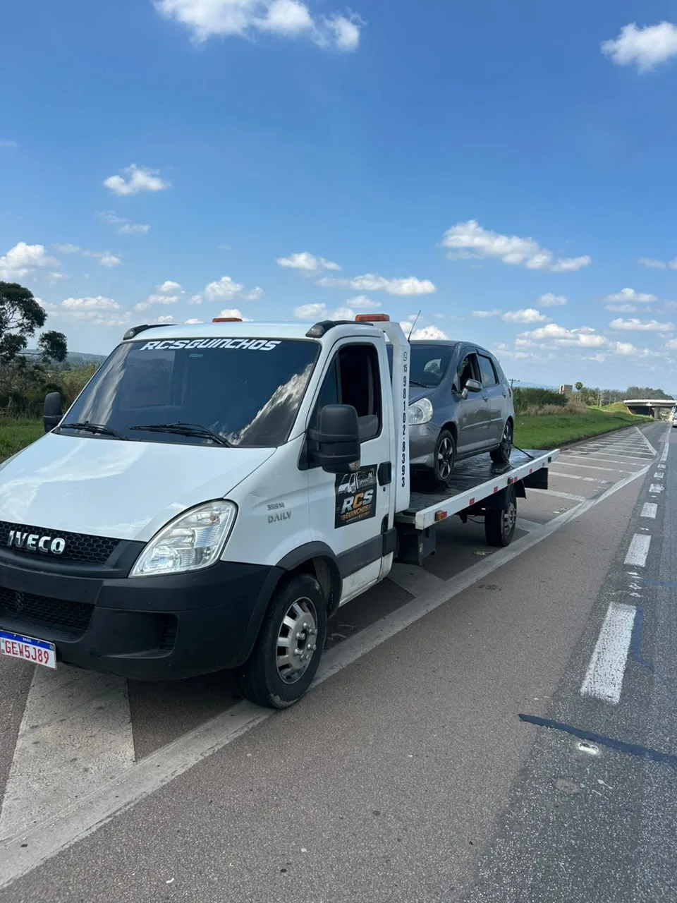 Guincho da RCS com carro na plataforma ao lado de uma rodovia durante o dia