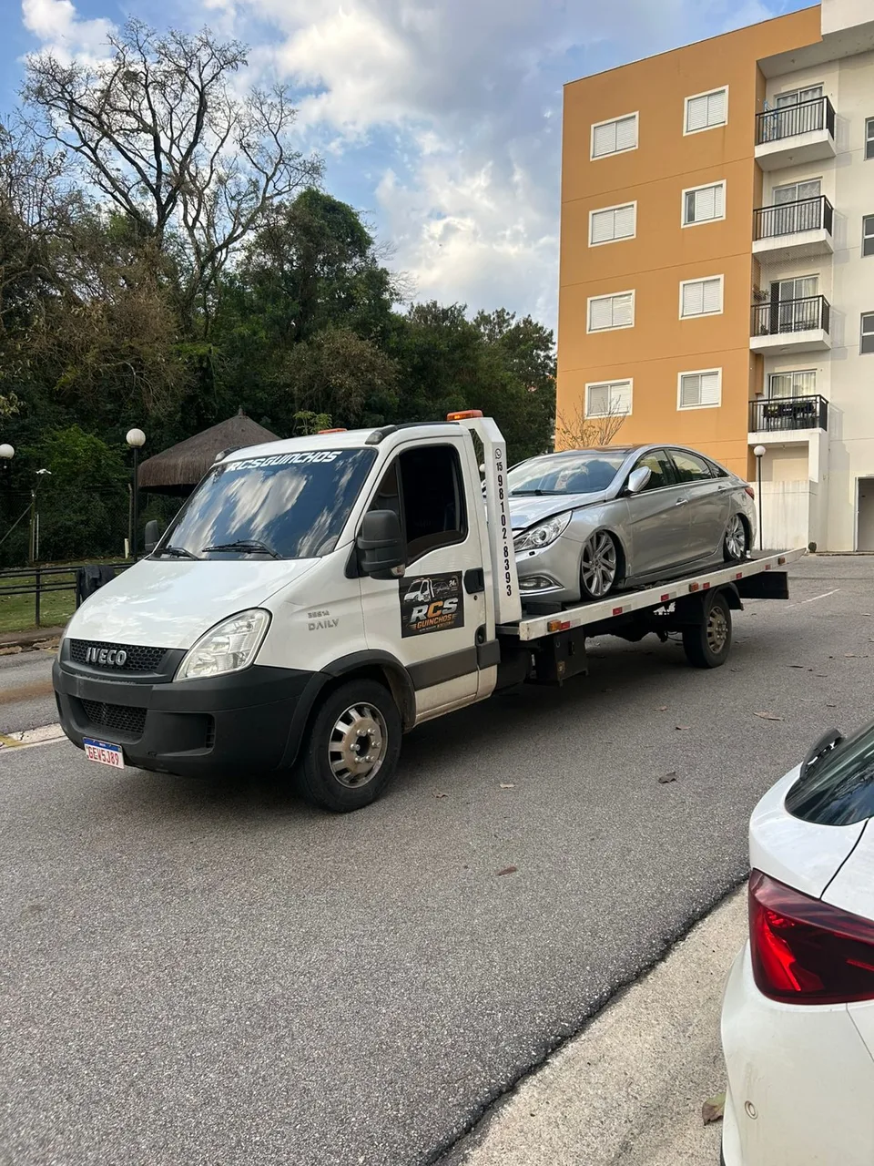 Guincho da RCS com carro na plataforma em frente a um edifício